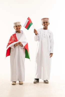 أطفال عمانيون يحملون العلم باللباس التقليدي العماني