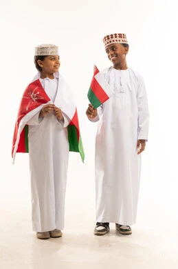 أطفال عمانيون بالزي التقليدي يحملون علم سلطنة عمان