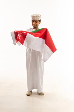 طفل عماني بالزي التقليدي يحمل علم عمان