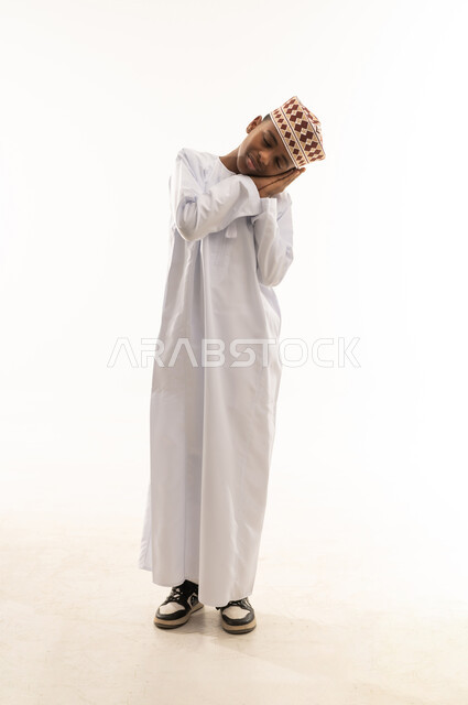 Omani Boy in Traditional Dishdasha Making Sleeping Gesture