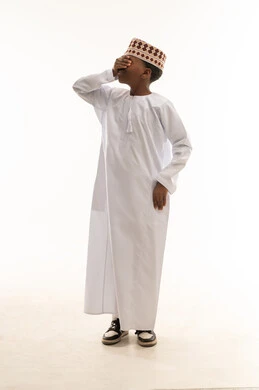 Omani Boy in Traditional Dishdasha Covering His Eyes