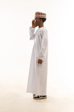 طفل عماني بالدشداشة والكمة التقليدية بخلفية بيضاء