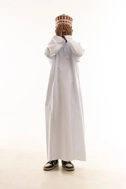 Omani Child in Traditional Dress Covering His Eyes