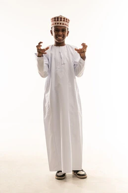 طفل عماني بالدشداشة والكمة التقليدية يقوم بإيماءة مرحة