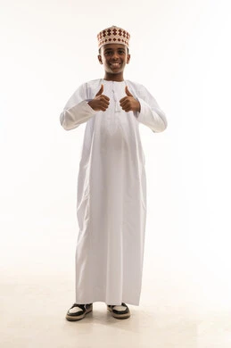 صبي عماني بالزي التقليدي يرفع إبهامه للتأييد