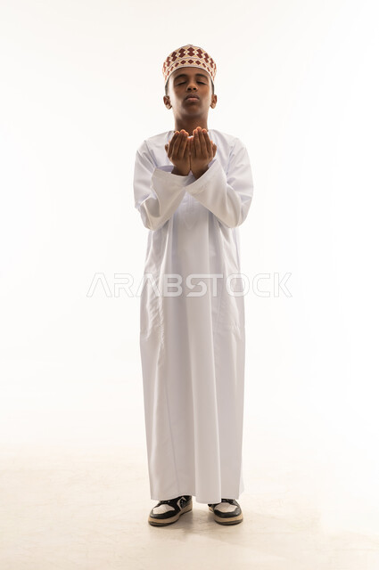 Omani Boy in Traditional Dishdasha Praying on White