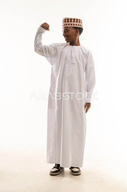 Omani Boy in Traditional Dishdasha Flexing Muscles