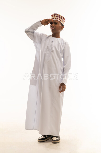 Omani Boy in Traditional Dishdasha Saluting on White Background