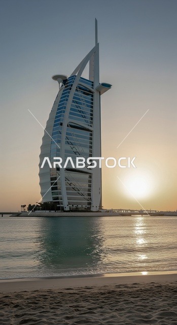 The unique architectural design of the Burj Al Arab in Dubai, the famous tourist attractions in the UAE, the view of the clear sky during the day, the hotel's extension on an artificial island in the Arabian Gulf.
