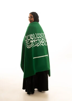 امرأة سعودية تلتف بالعلم السعودي على خلفية بيضاء