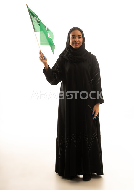 امرأة سعودية بالعباءة السوداء تحمل علم السعودية