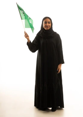 امرأة سعودية بالعباءة السوداء تحمل علم السعودية