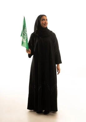 امرأة سعودية تحمل العلم الوطني على خلفية بيضاء