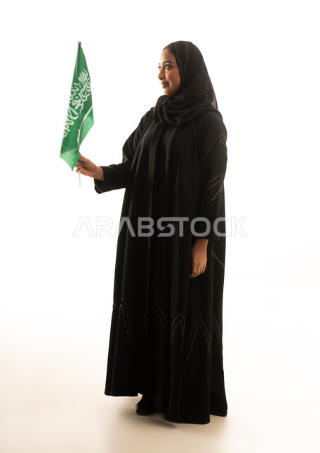 امرأة سعودية بالعباءة السوداء تحمل علم السعودية