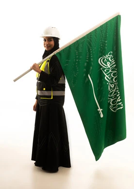 مهندسة سعودية مع العلم الوطني بخلفية بيضاء
