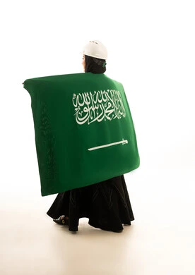 مهندسة سعودية تحمل العلم السعودي على خلفية بيضاء