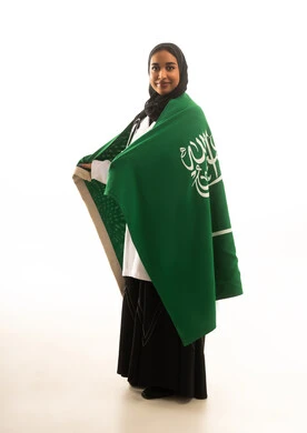 طبيبة سعودية تلتف بالعلم الوطني السعودي