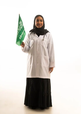 طبيبة سعودية تحمل العلم السعودي على خلفية بيضاء