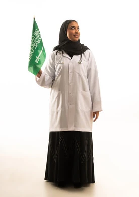 طبيبة سعودية تحمل العلم السعودي على خلفية بيضاء