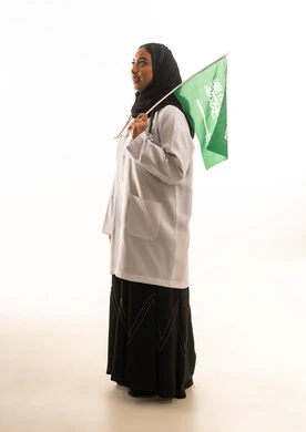 طبيبة سعودية تحمل العلم الوطني خلفية بيضاء