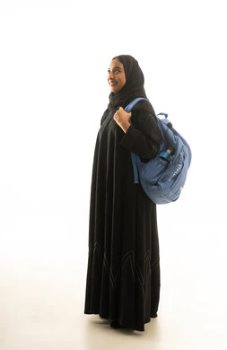 طالبة سعودية تحمل حقيبة ظهر على خلفية بيضاء