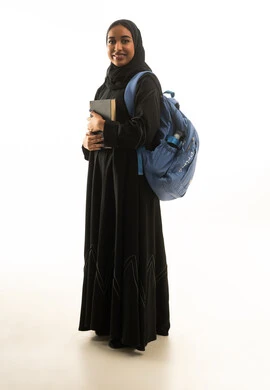 طالبة سعودية ترتدي العباءة وتحمل حقيبة ظهر وكتاب