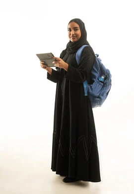 طالبة سعودية تحمل جهاز لوحي وحقيبة ظهر خلفية بيضاء