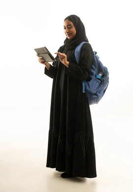 امرأة سعودية تستخدم جهازاً لوحياً مع حقيبة ظهر امرأة سعودية تستخدم جهازاً لوحياً مع حقيبة ظهر