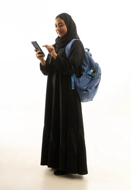 طالبة سعودية بالعباءة تستخدم الجوال وتحمل حقيبة