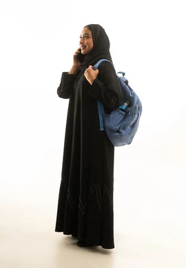 طالبة سعودية بالعباية مع هاتف وحقيبة ظهر