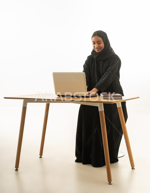 امرأة سعودية تستخدم الحاسوب المحمول خلفية بيضاء
