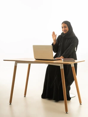 امرأة سعودية تستخدم اللابتوب لمكالمة فيديو على المكتب