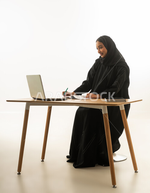 امرأة سعودية تعمل على كمبيوتر محمول على مكتب