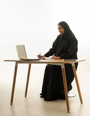 امرأة سعودية تعمل على كمبيوتر محمول على مكتب