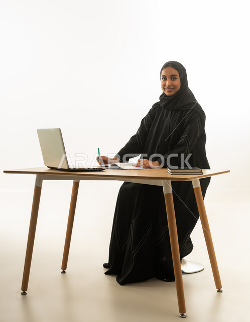 امرأة سعودية مع كمبيوتر محمول على مكتب خلفية بيضاء