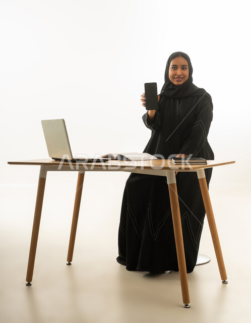 سيدة أعمال سعودية تحمل هاتف ذكي أمام المكتب