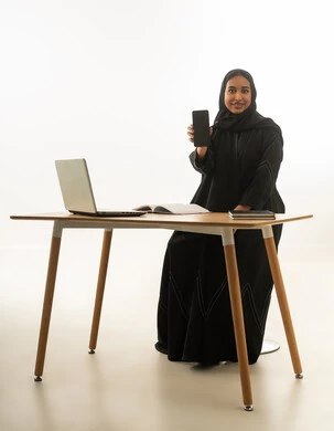 Saudi Businesswoman Holding Smartphone at Desk