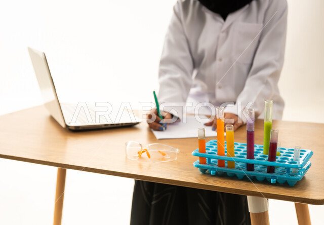 Saudi Female Scientist Writing at Laboratory Desk