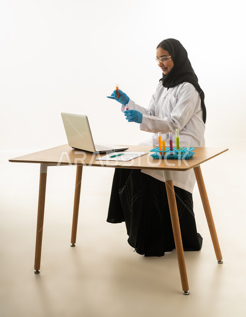 عالمة سعودية تعمل على الحاسوب وعينات المختبر