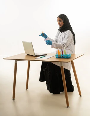 عالمة سعودية تعمل على الحاسوب وعينات المختبر