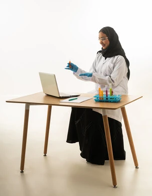 عالمة سعودية مع كمبيوتر محمول وأنابيب اختبار