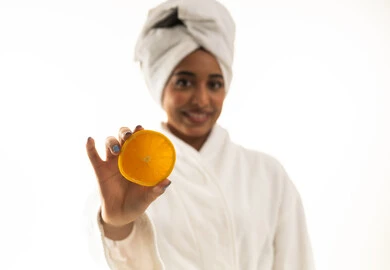 امرأة سعودية برداء الاستحمام تحمل شريحة برتقال