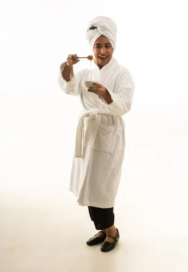 امرأة سعودية برداء حمام أبيض تحضر قناع العسل