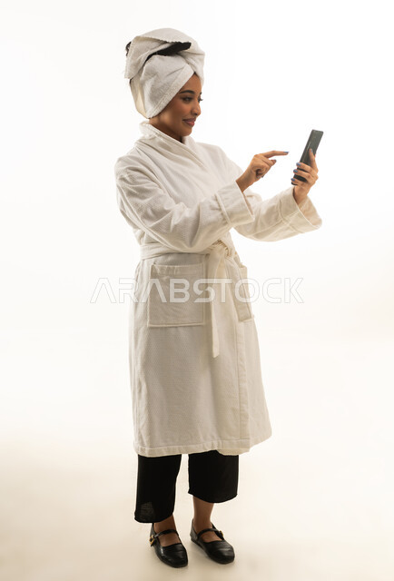 Saudi Woman in Bathrobe Using Smartphone on White