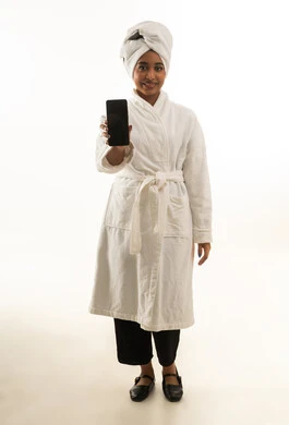 امرأة سعودية برداء الحمام تحمل هاتفاً ذكياً خلفية بيضاء