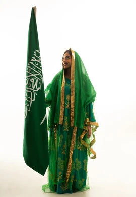 امرأة سعودية بالزي التقليدي تحمل علم المملكة