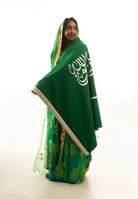 فتاة سعودية بالزي التقليدي مع العلم الوطني