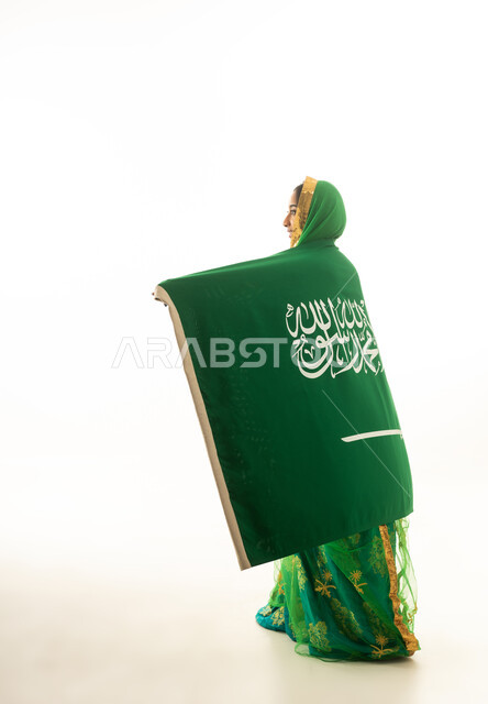 امرأة سعودية مع العلم الوطني بالزي التقليدي