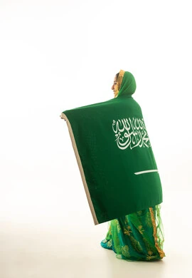 امرأة سعودية مع العلم الوطني بالزي التقليدي