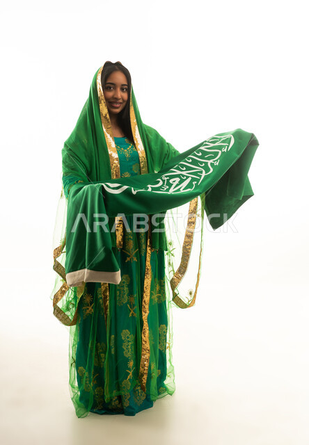 امرأة سعودية بالزي التقليدي تحمل العلم الوطني